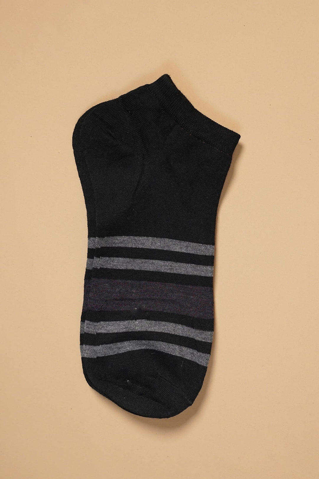 Black ankle sock with gray stripes on a beige background.